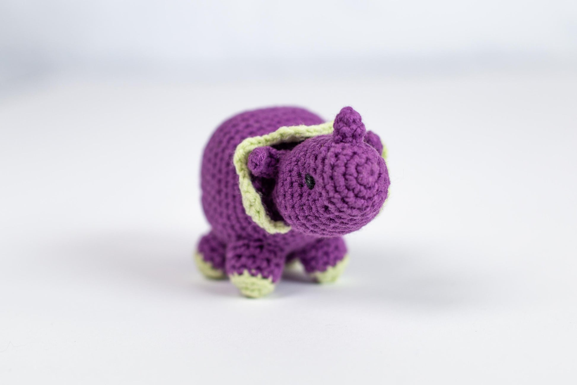 a small crocheted purple elephant toy on a white surface