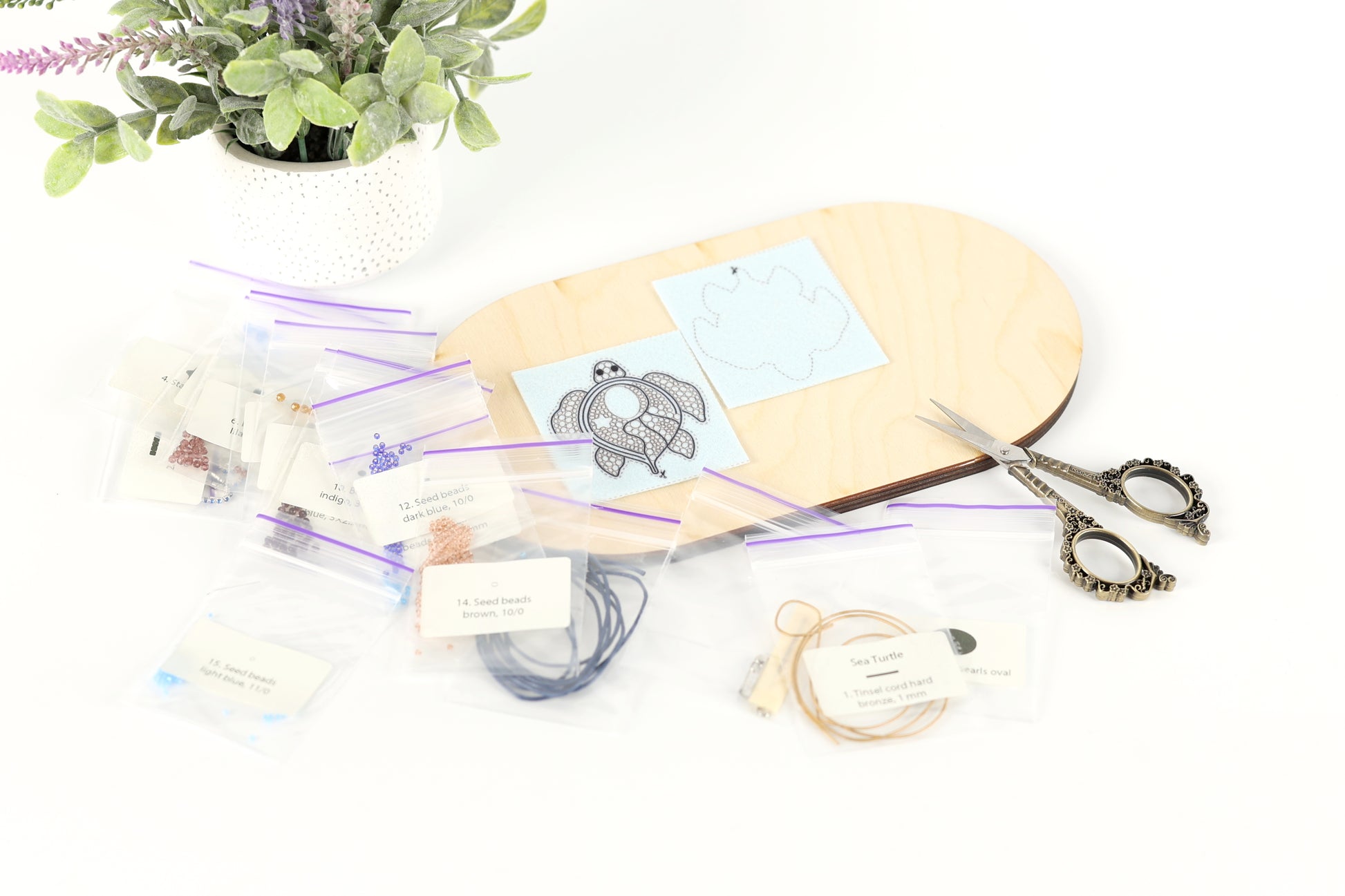 a crafting area with various supplies and materials, including a wooden board, scissors, and a potted plant.