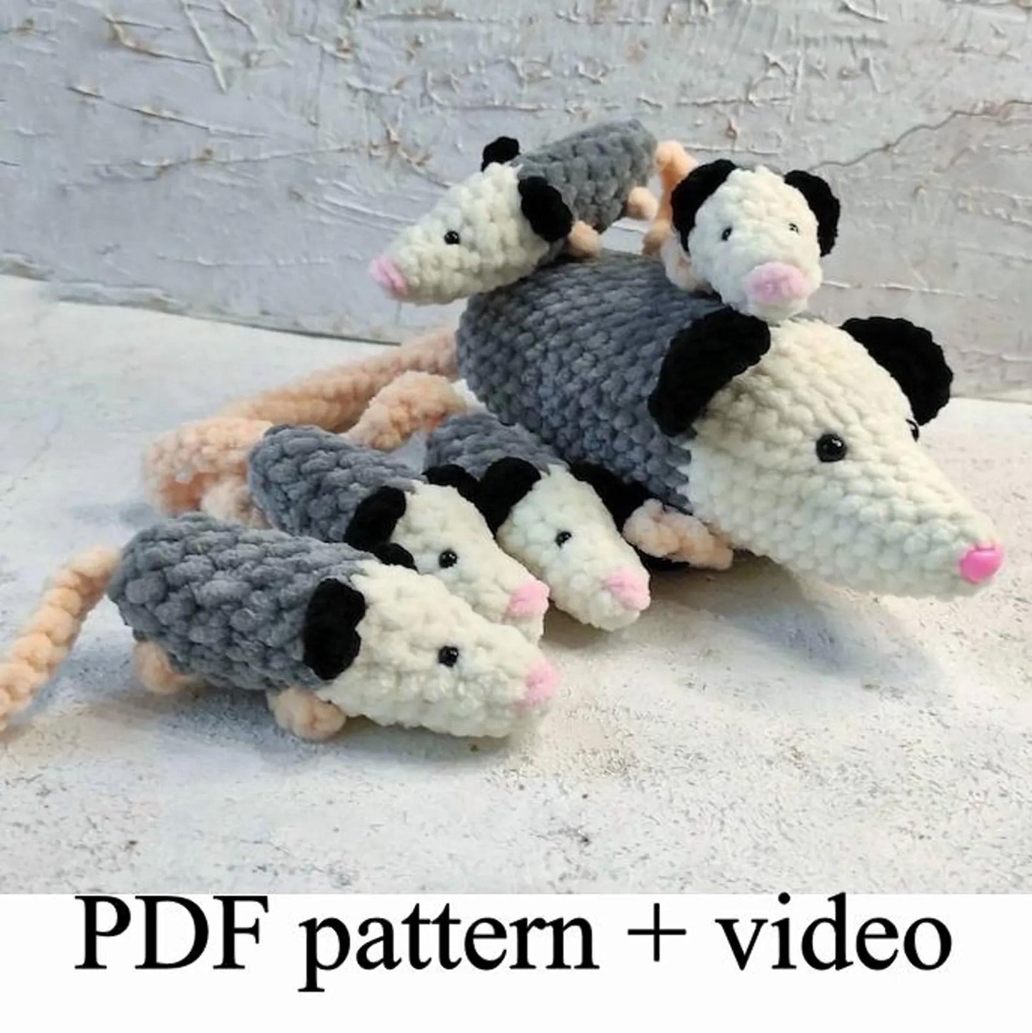 A group of crocheted opossum toys, including a mother opossum and her three offspring, arranged on a white surface.