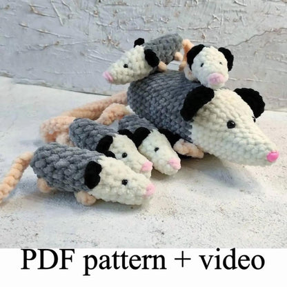 A group of crocheted opossum toys, including a mother opossum and her three offspring, arranged on a white surface.