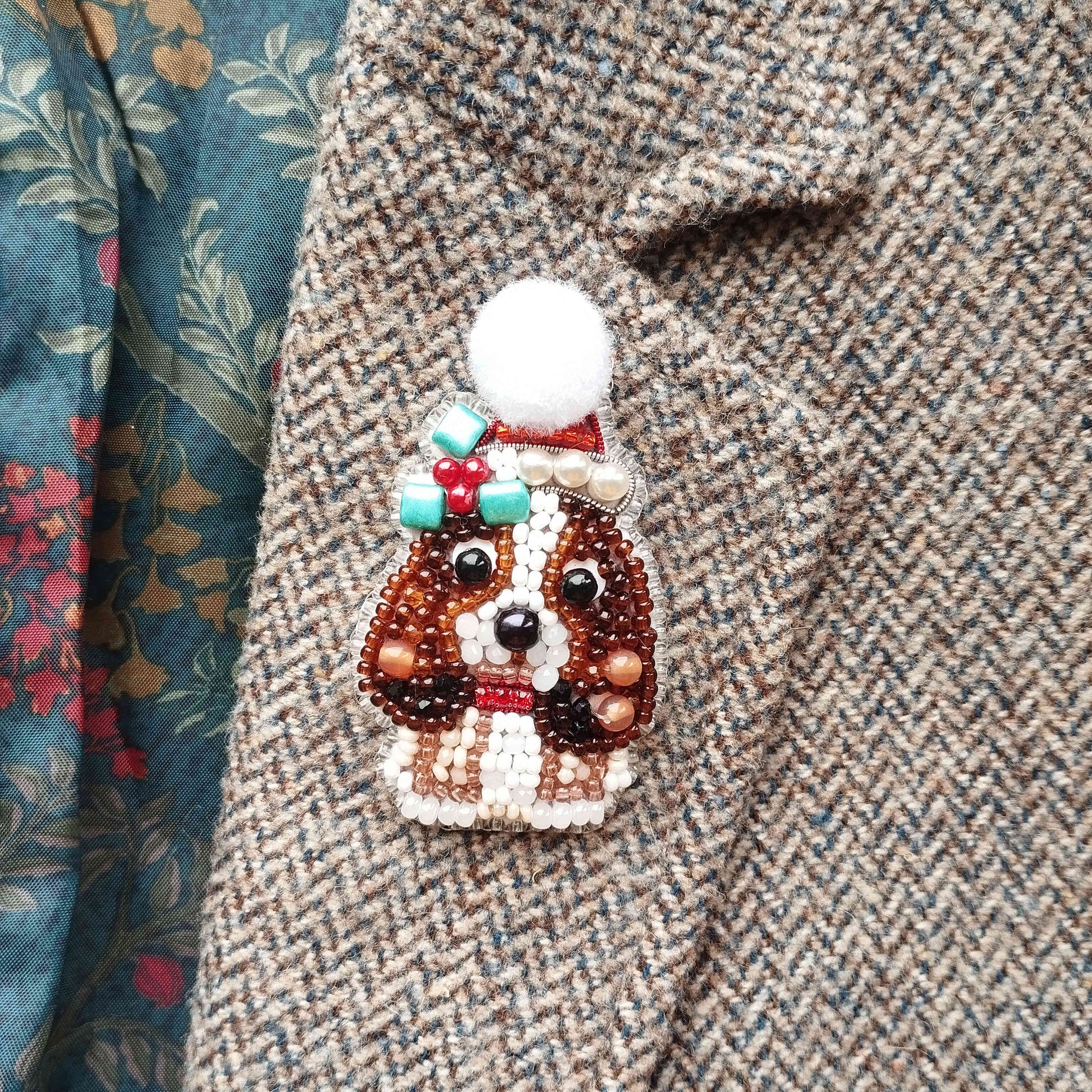 A close-up of a beaded dog brooch on a tweed jacket.