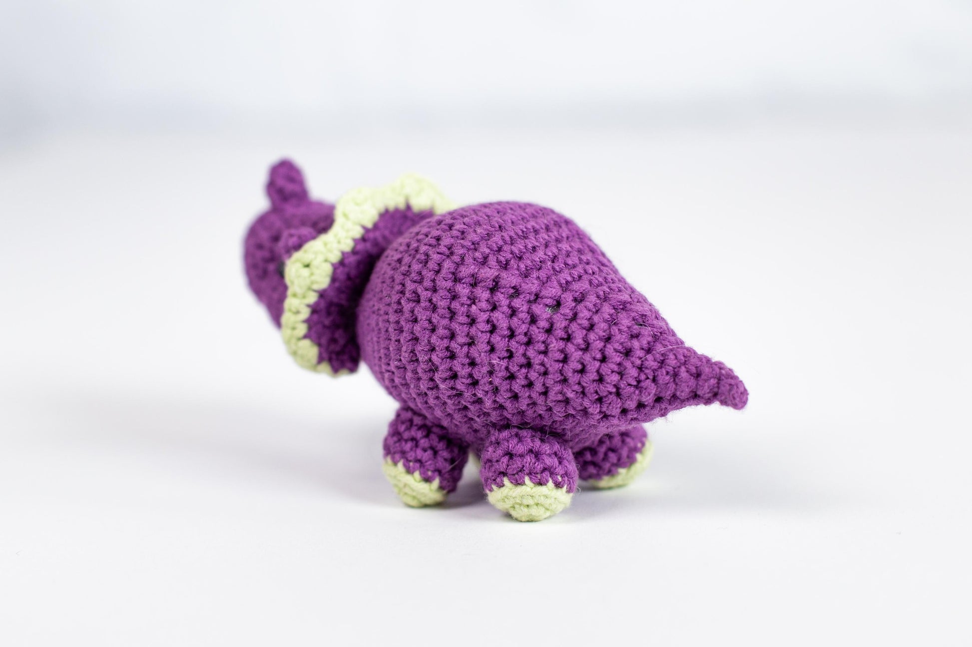 a crocheted purple turtle with a green tail
