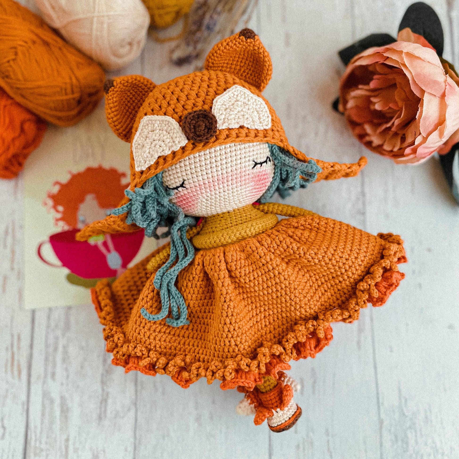 a crocheted fox doll sitting on top of a wooden floor