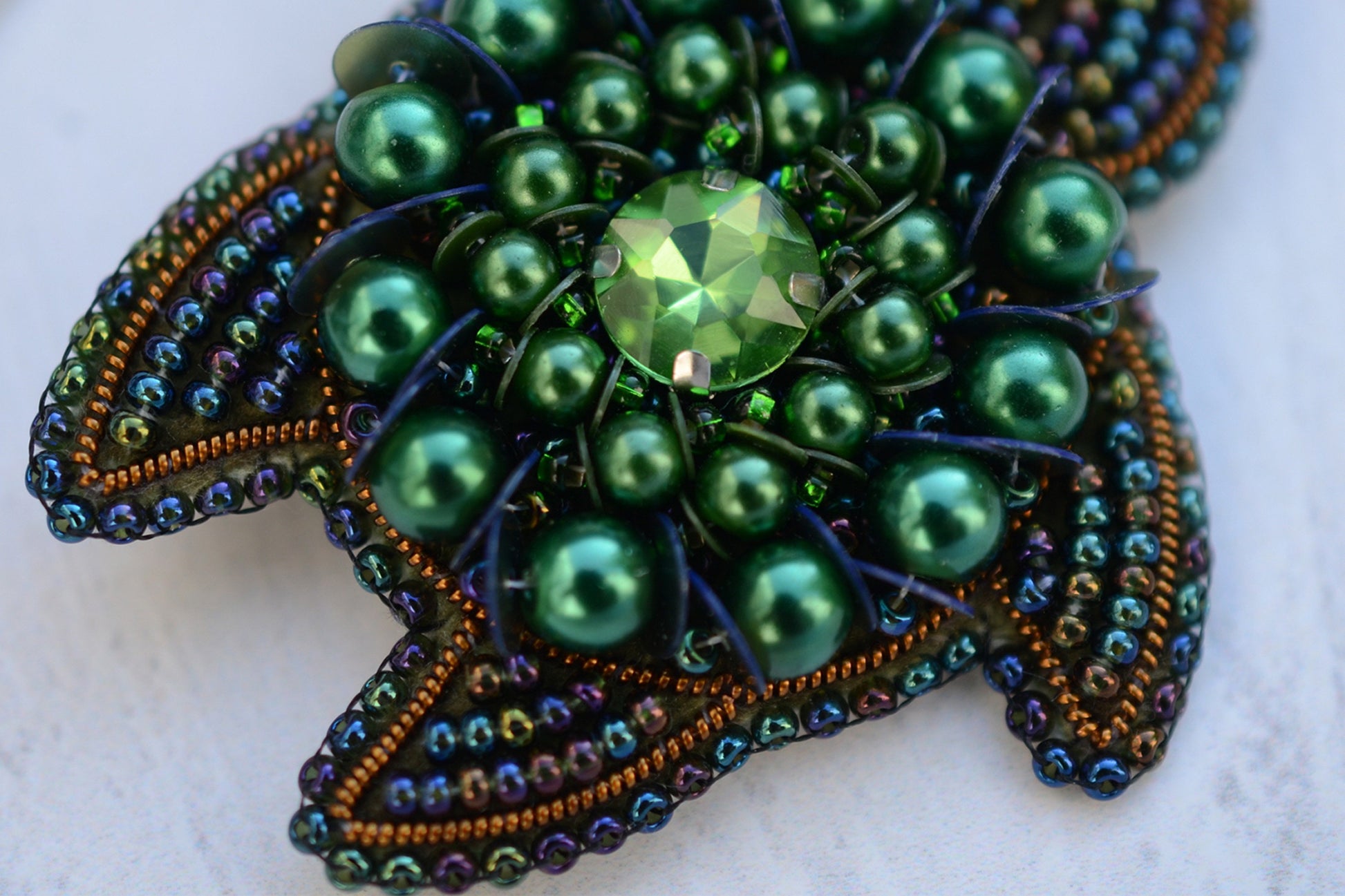 a close up of a brooch on a white surface