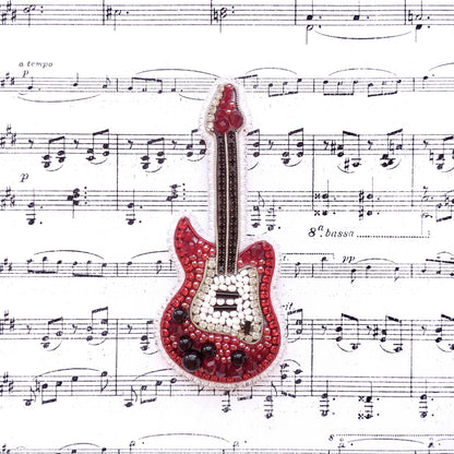 A red and white guitar-shaped embellishment is placed on top of sheet music with musical notes surrounding it.