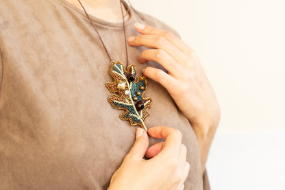 a woman wearing a necklace that has a leaf on it