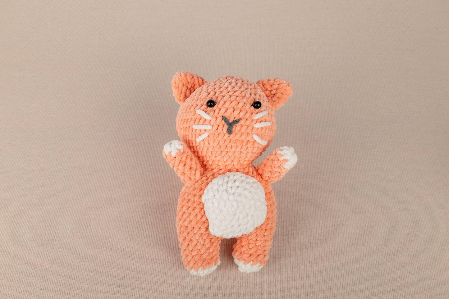 a small crocheted orange cat sitting on top of a table