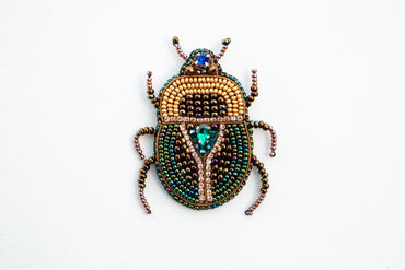 a beaded beetle sitting on top of a white surface