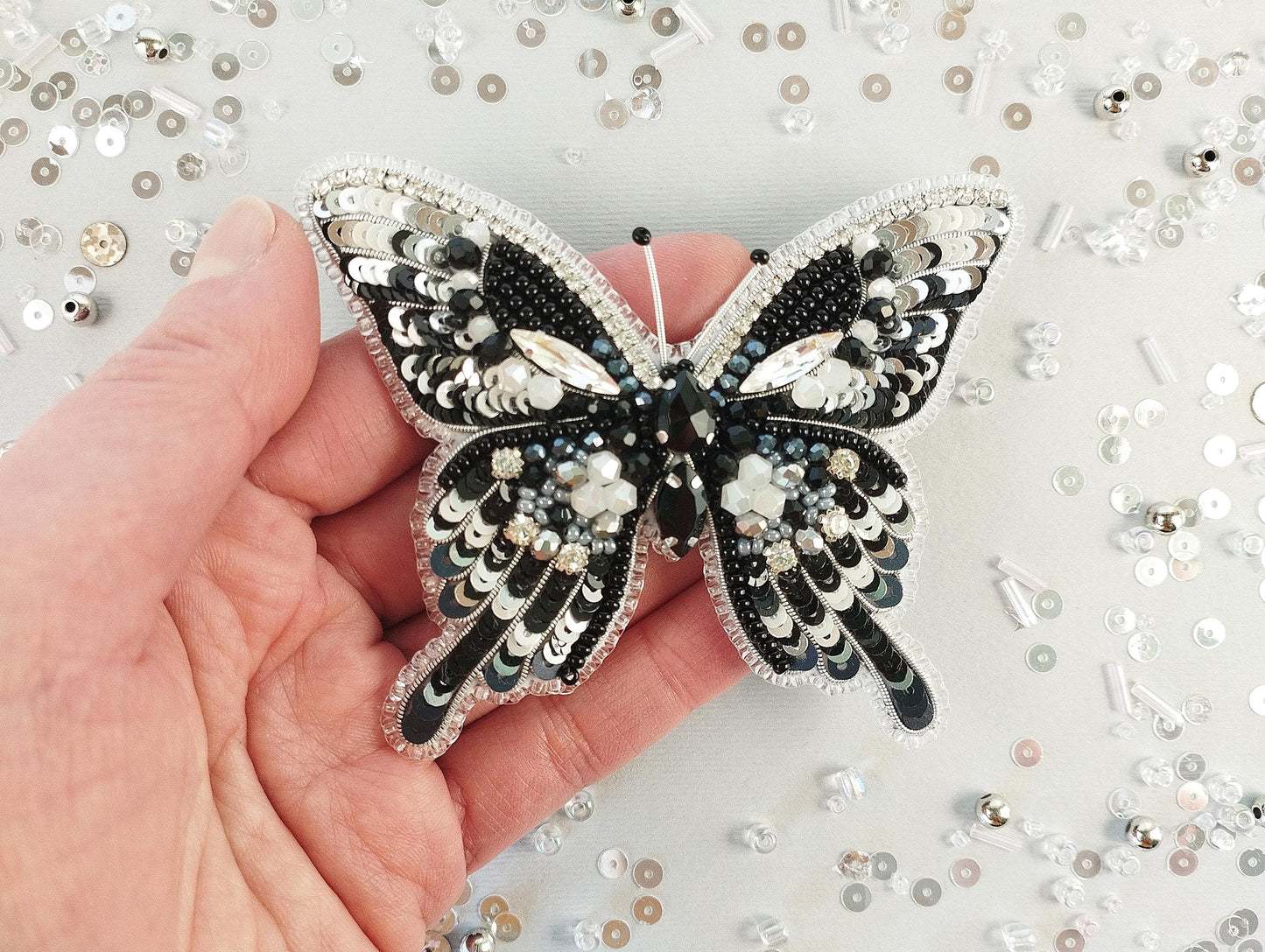 a hand holding a black and white butterfly brooch