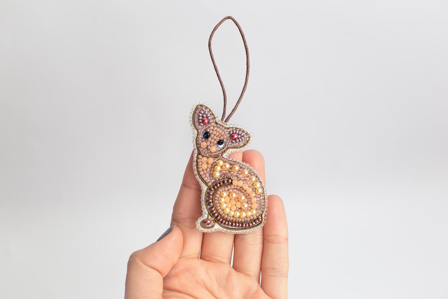 a hand holding a beaded animal ornament