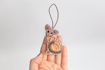 a hand holding a beaded animal ornament