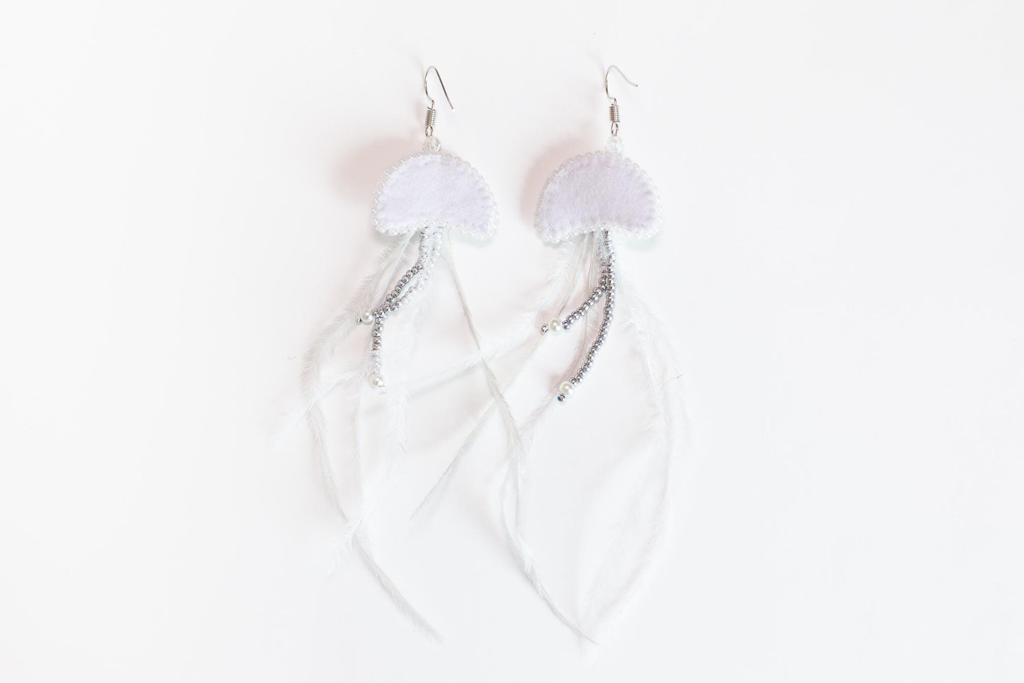 a pair of earrings with white feathers on a white background