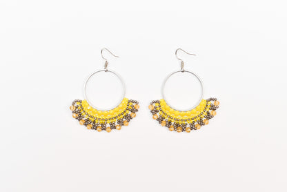 A pair of earrings with a yellow and black color scheme, featuring a circular design with a beaded or sequined trim.