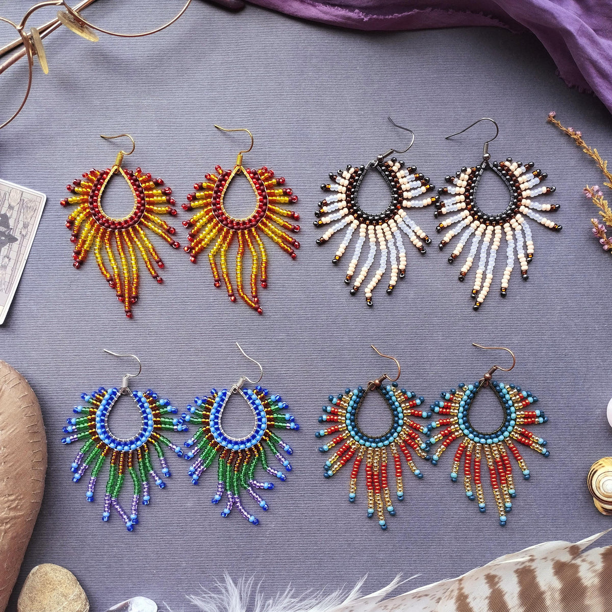 a collection of earrings with various colors and designs, arranged on a gray surface.