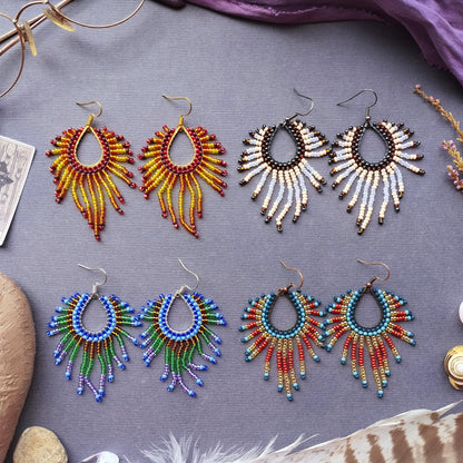 a collection of earrings with various colors and designs, arranged on a gray surface.
