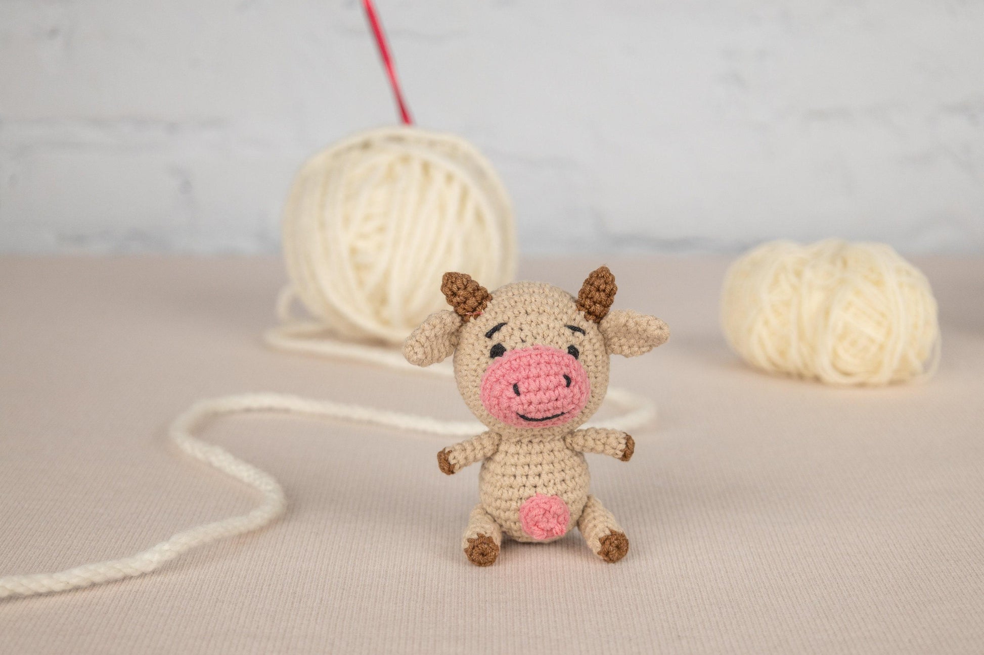 a small stuffed cow sitting next to a ball of yarn