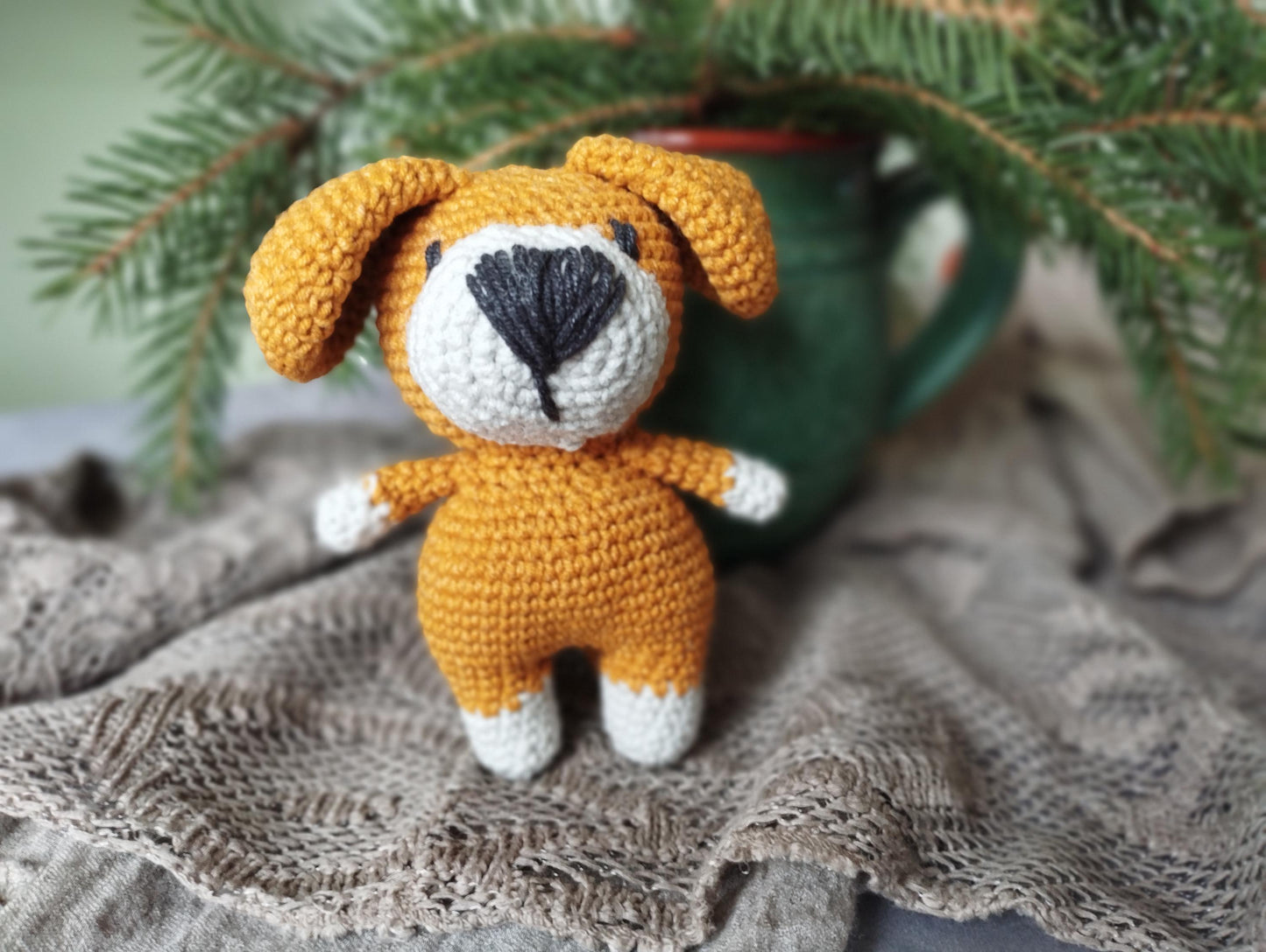 a crocheted dog sitting next to a cup of coffee