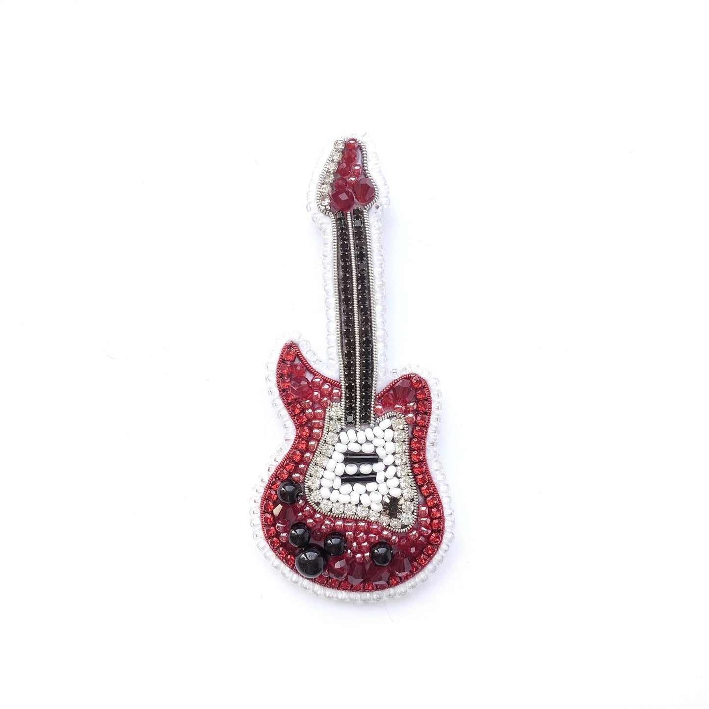 A red and white guitar-shaped pin made of beads and sequins against a white background.