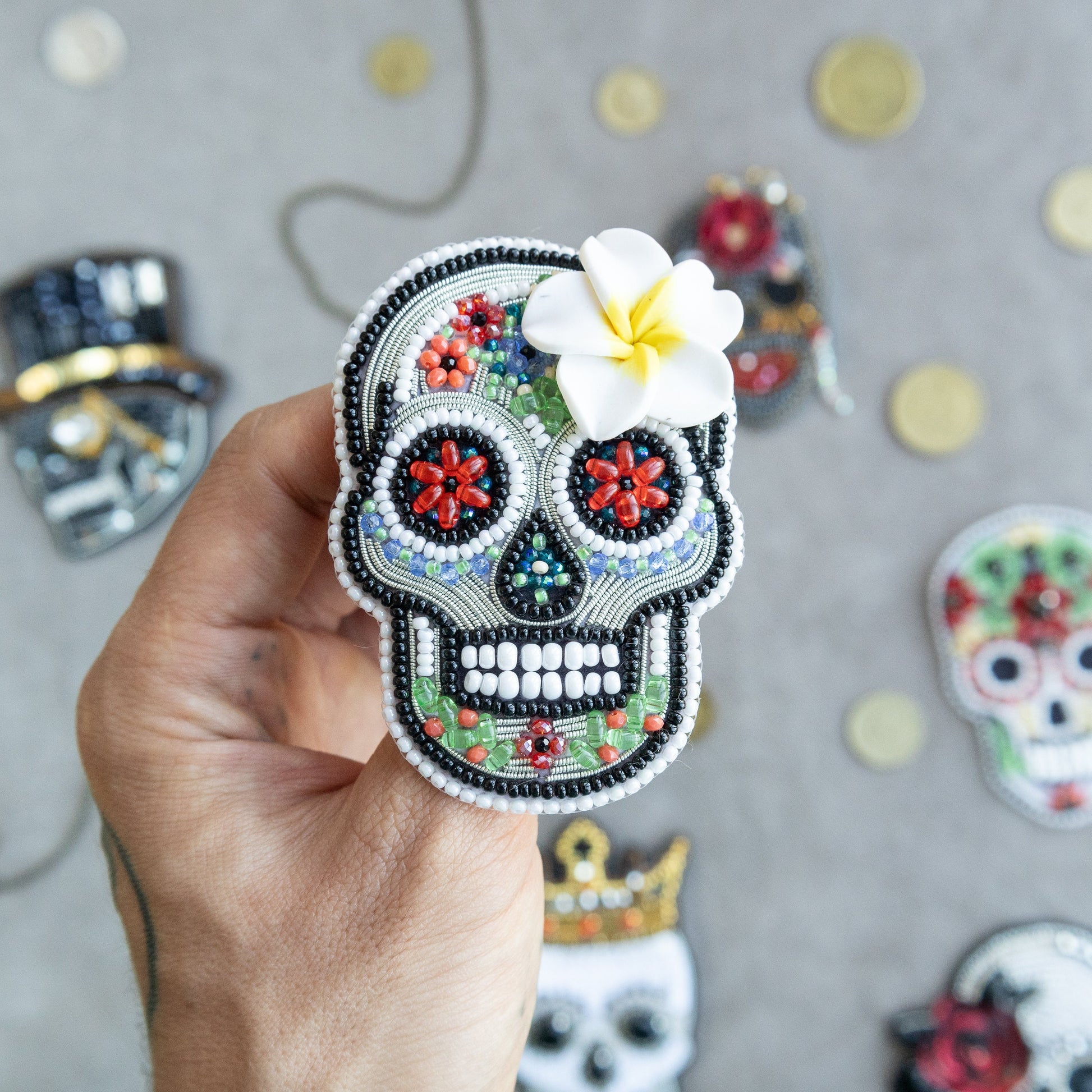 a hand holding a small sugar skull with a flower in it