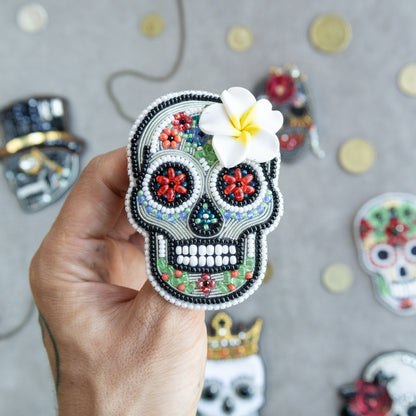 a hand holding a small sugar skull with a flower in it