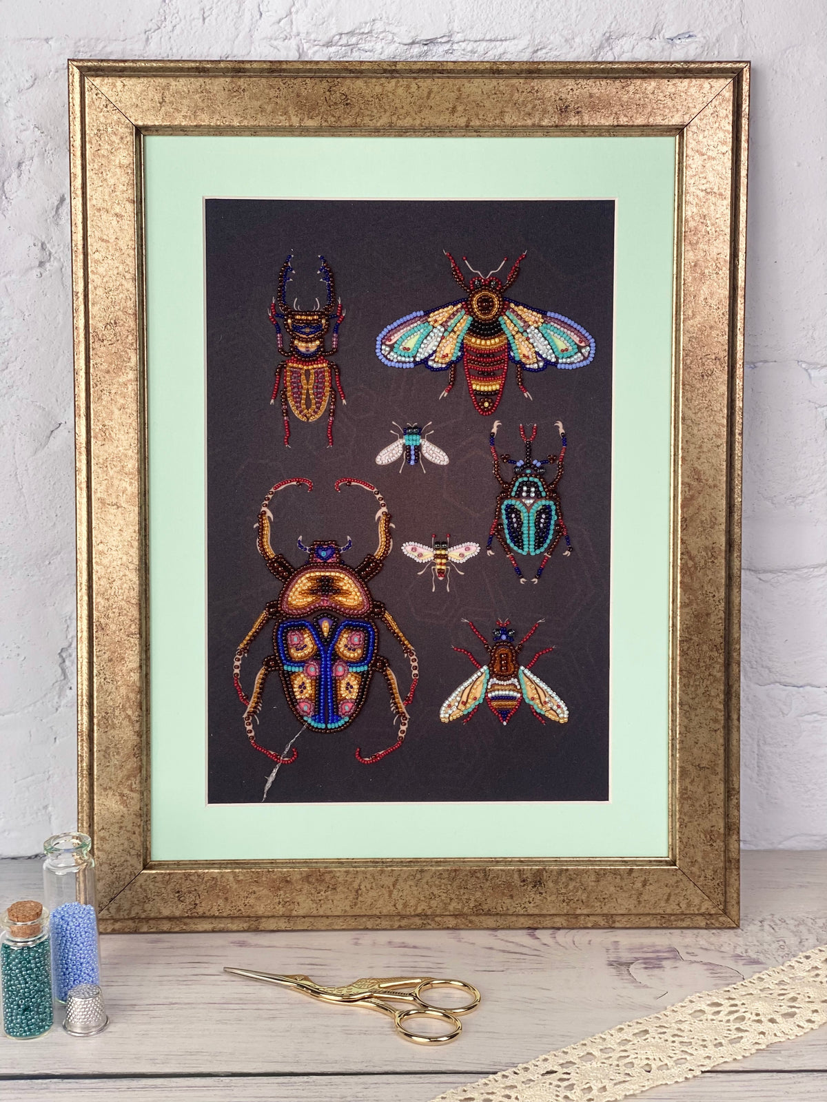 a framed artwork of colorful insects, including a large dragonfly, a bee, and several other insects, all set against a dark background.