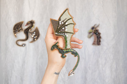 A hand holding a decorative dragon-shaped object with intricate details and embellishments.