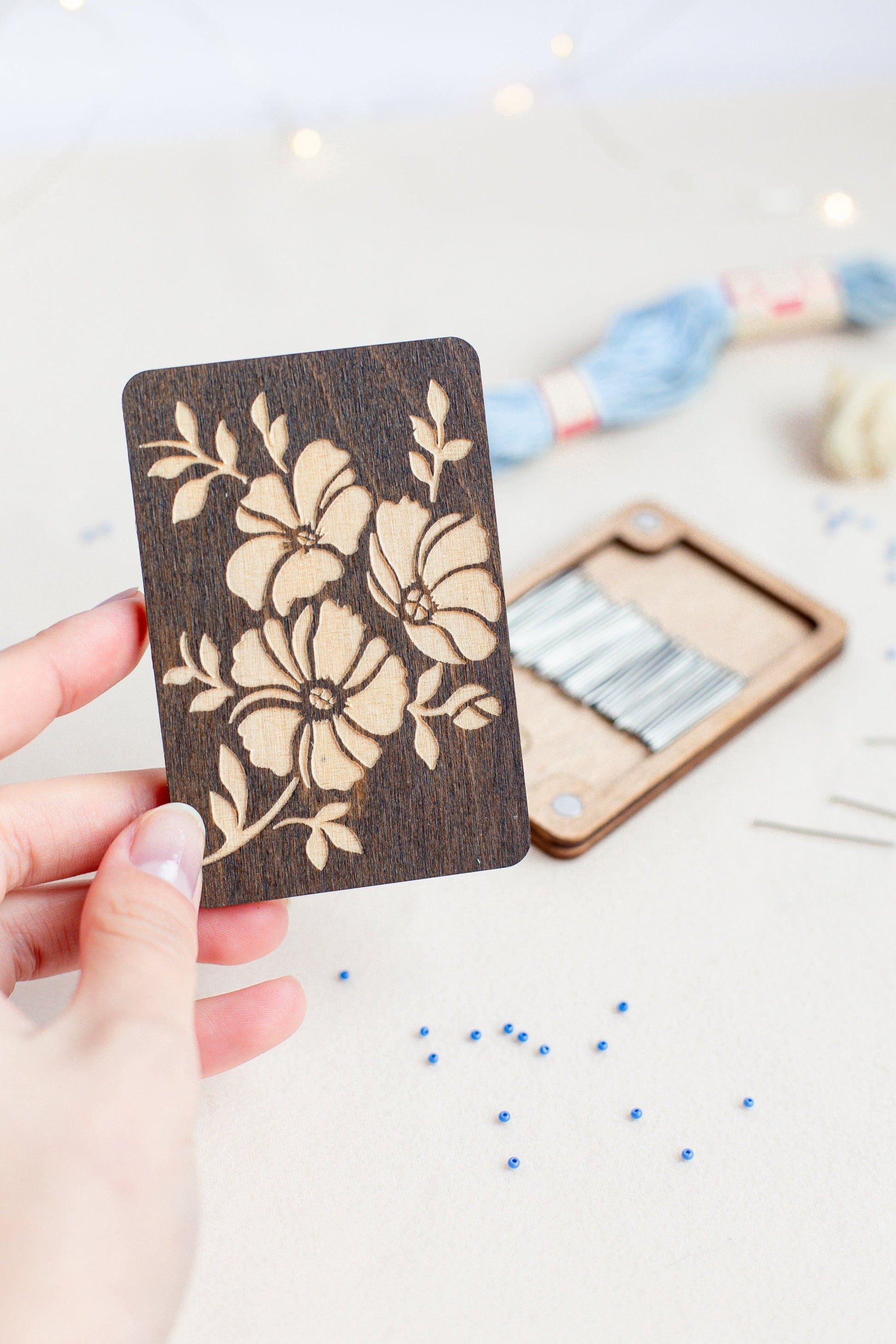 a person holding a wooden card with a flower design on it