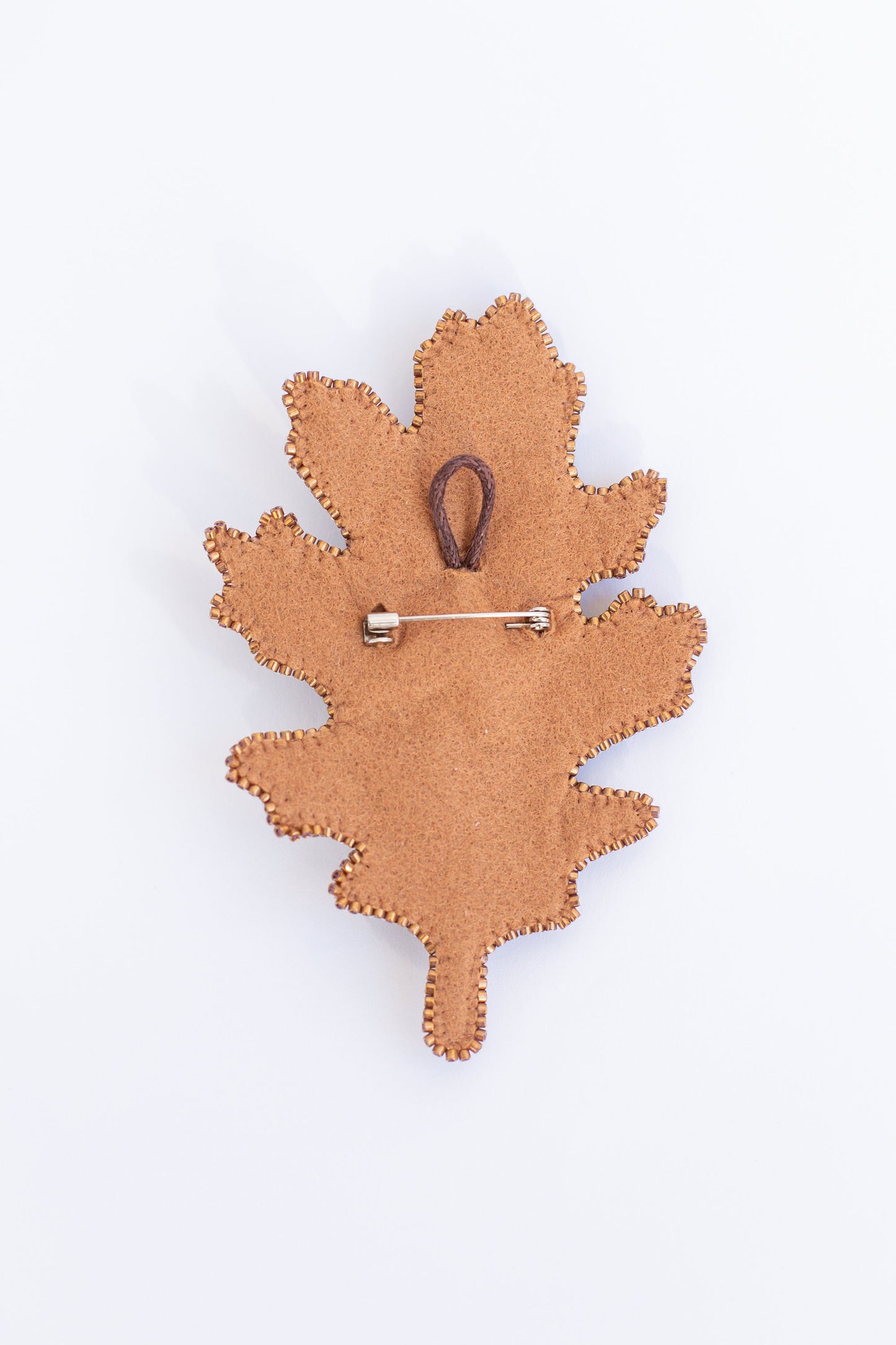 a wooden brooch with a leaf design on it
