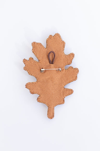a wooden brooch with a leaf design on it