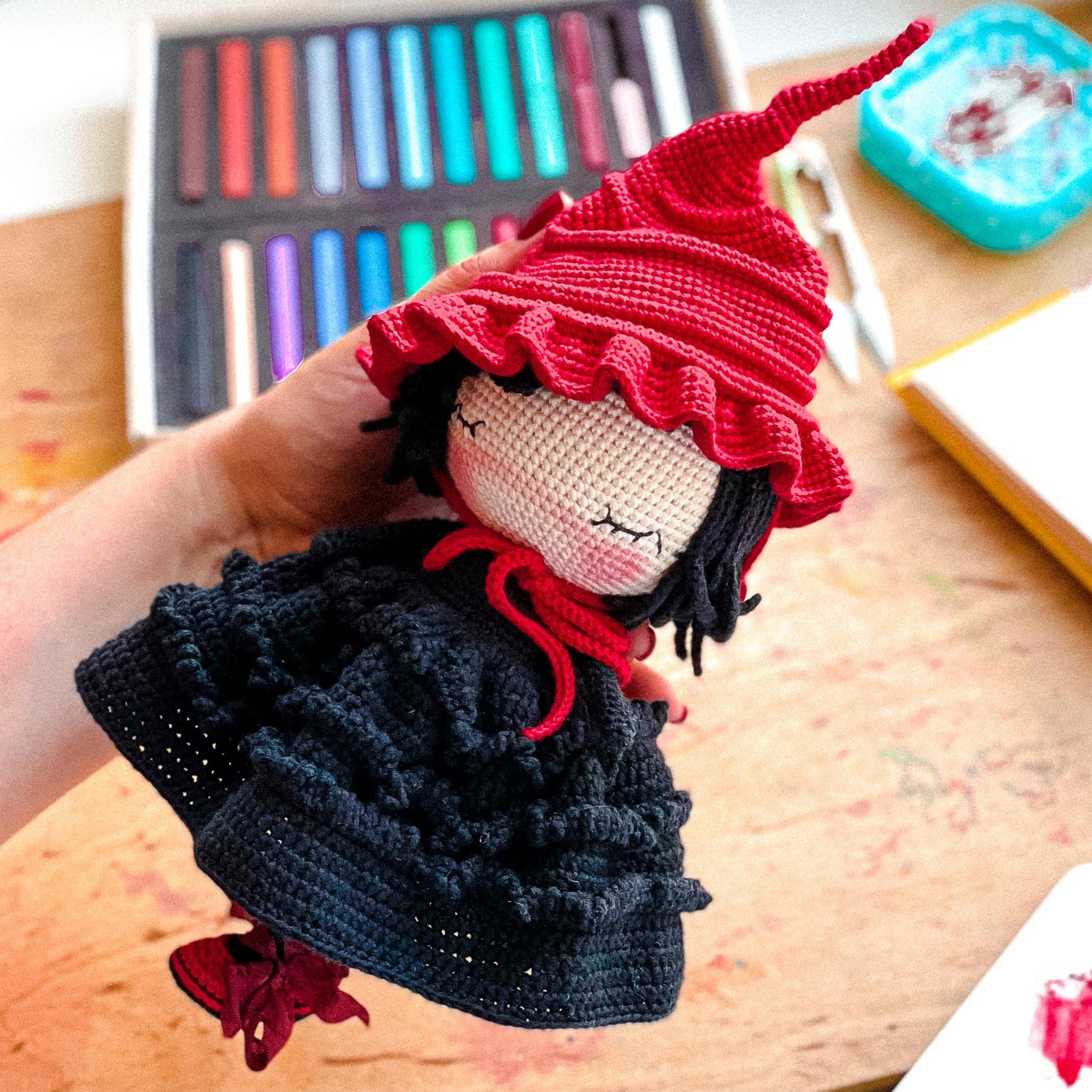 a hand holding a doll with a red hat