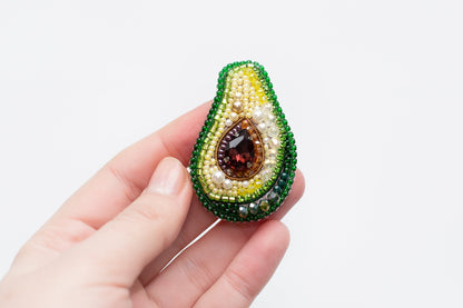 a person holding a beaded brooch in their hand