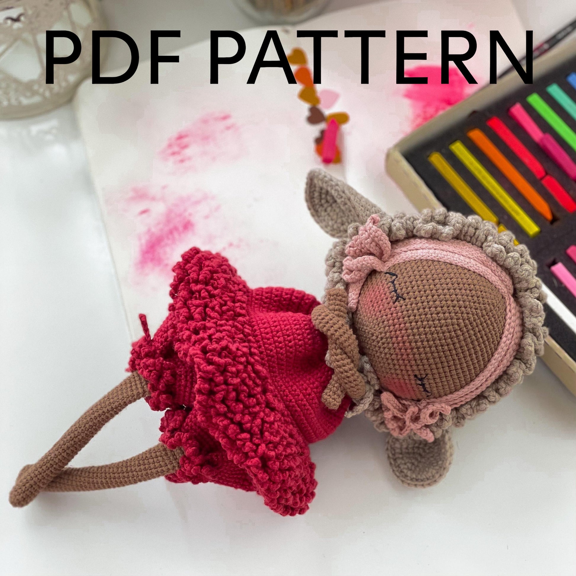 a knitted doll laying on top of a table next to a crayon