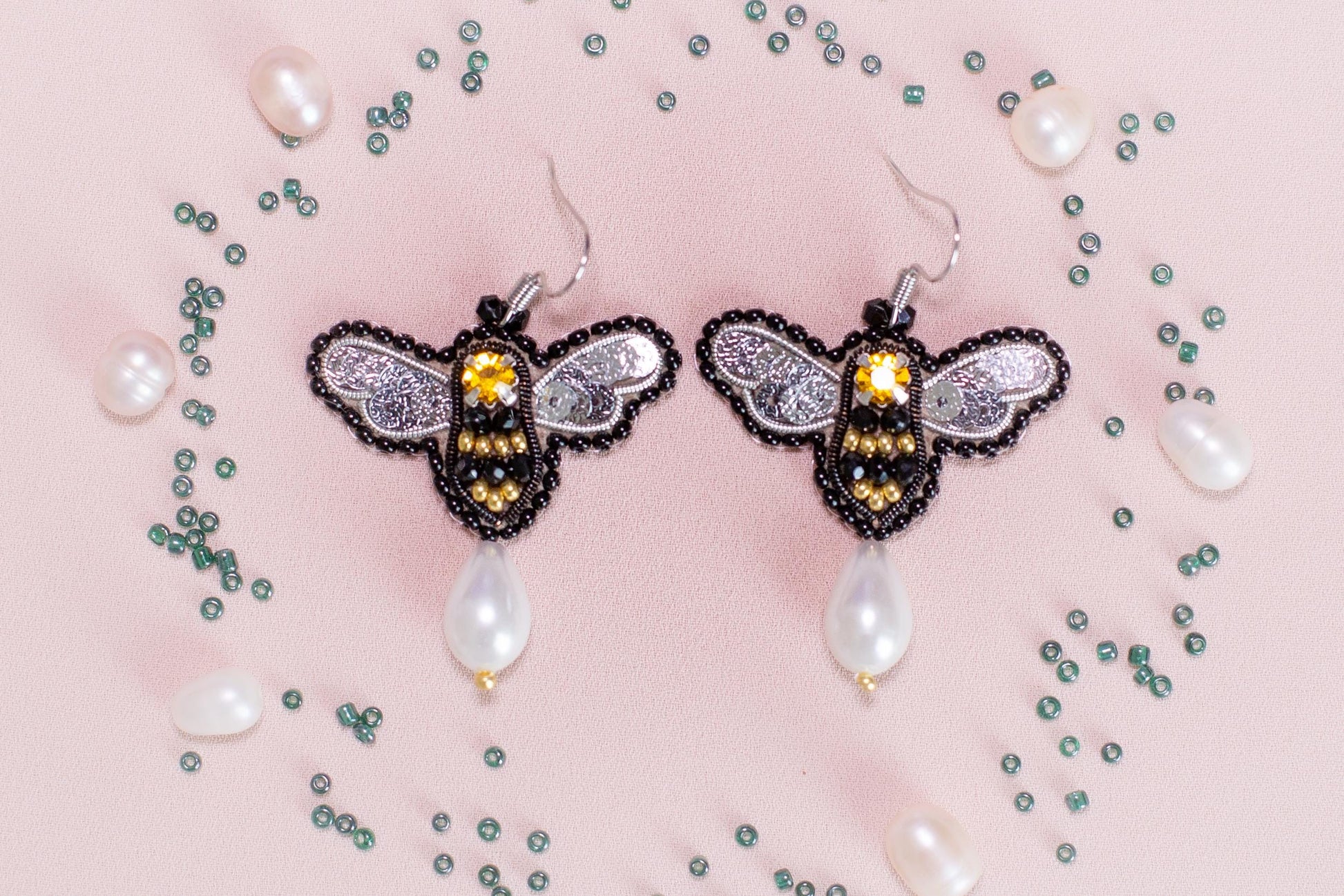 a pair of earrings with a bee on it