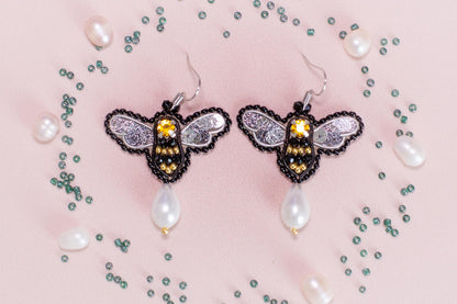 a pair of earrings with a bee on it