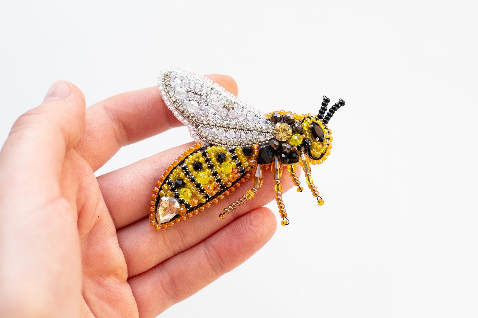 a hand holding a yellow and black beaded insect