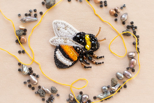 a beaded bee sitting on top of a yellow string