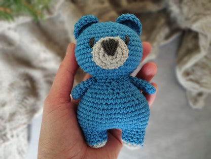 a crocheted blue teddy bear with a black nose