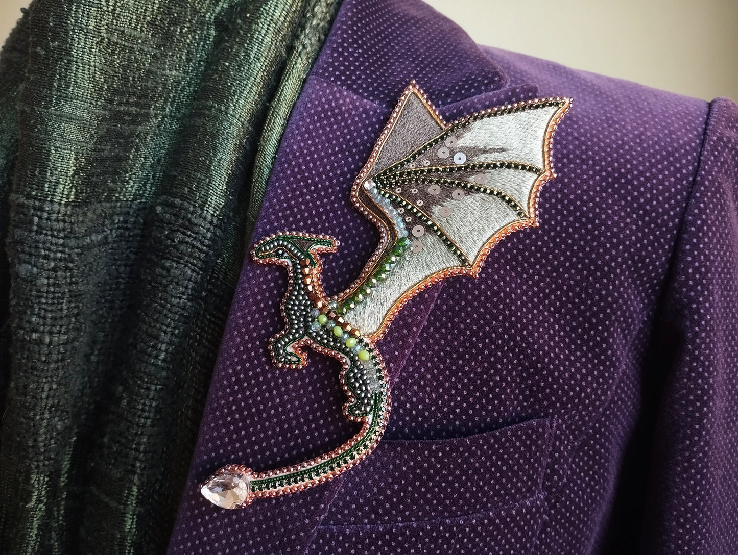 A purple jacket with a decorative dragon pin or brooch on the lapel.