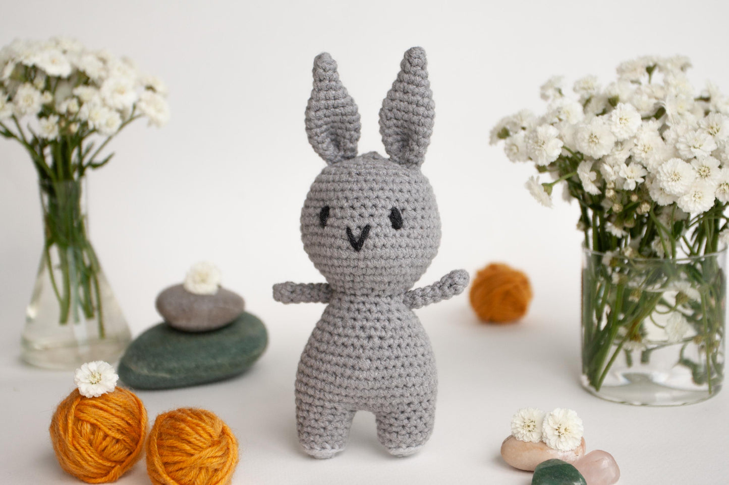 a crocheted bunny standing next to a vase of flowers