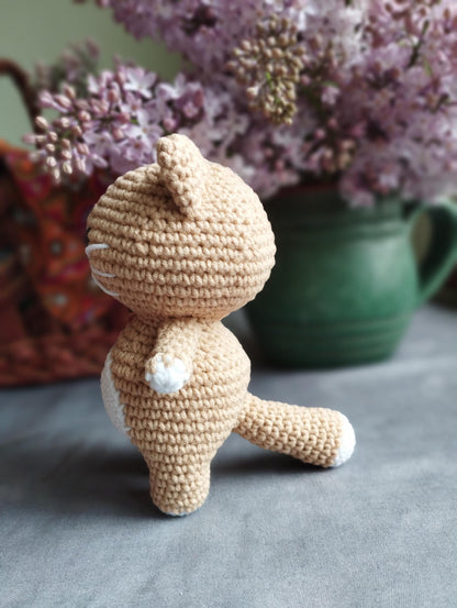 a crocheted teddy bear sitting next to a vase of flowers
