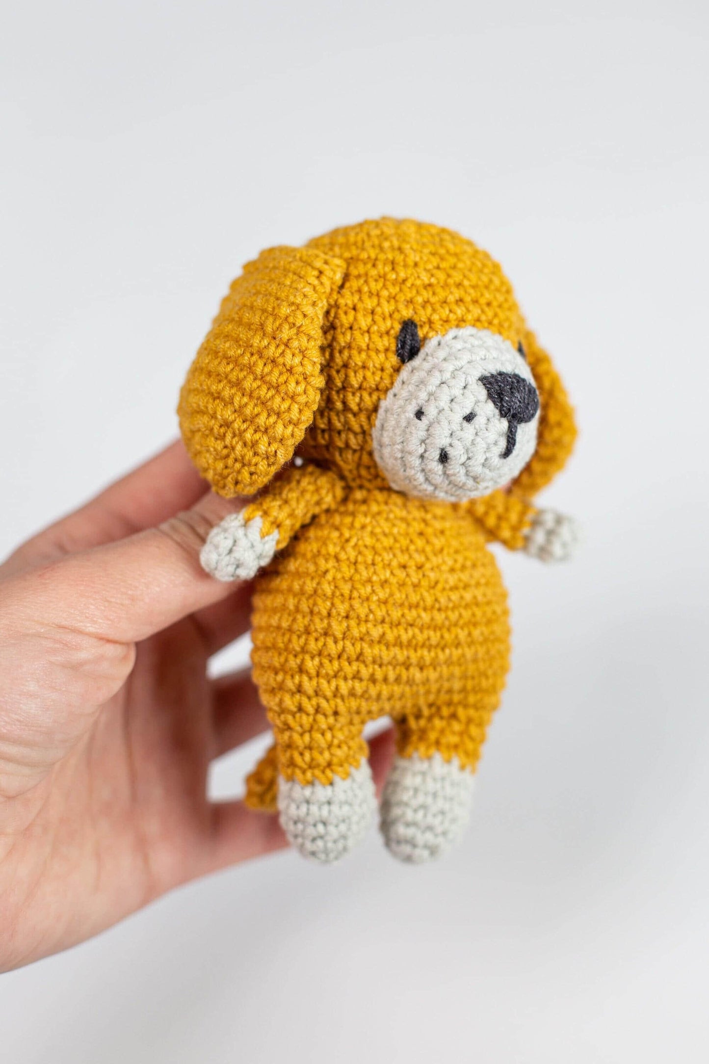 a hand holding a small yellow stuffed animal