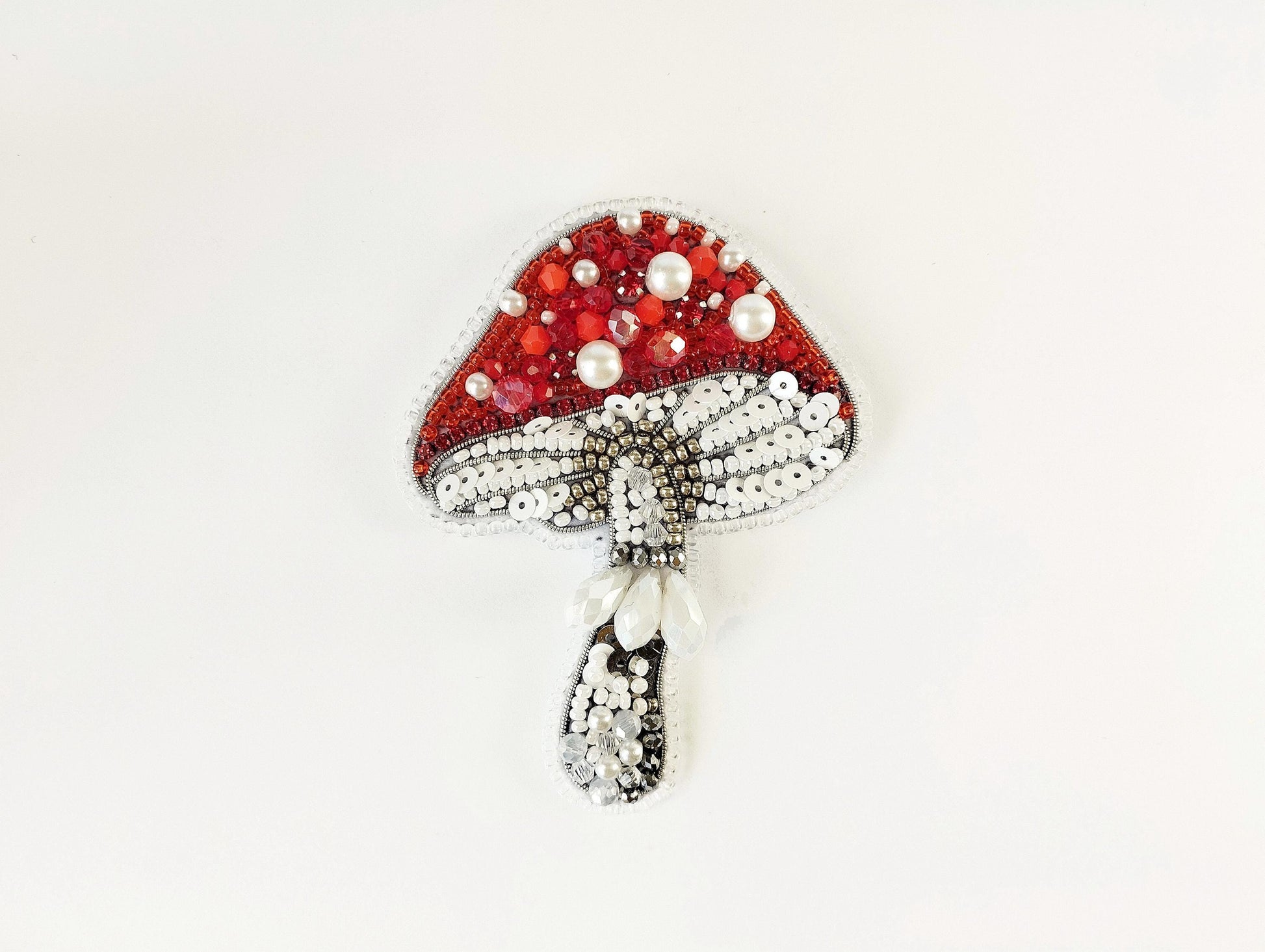 a red and white brooch with pearls on it