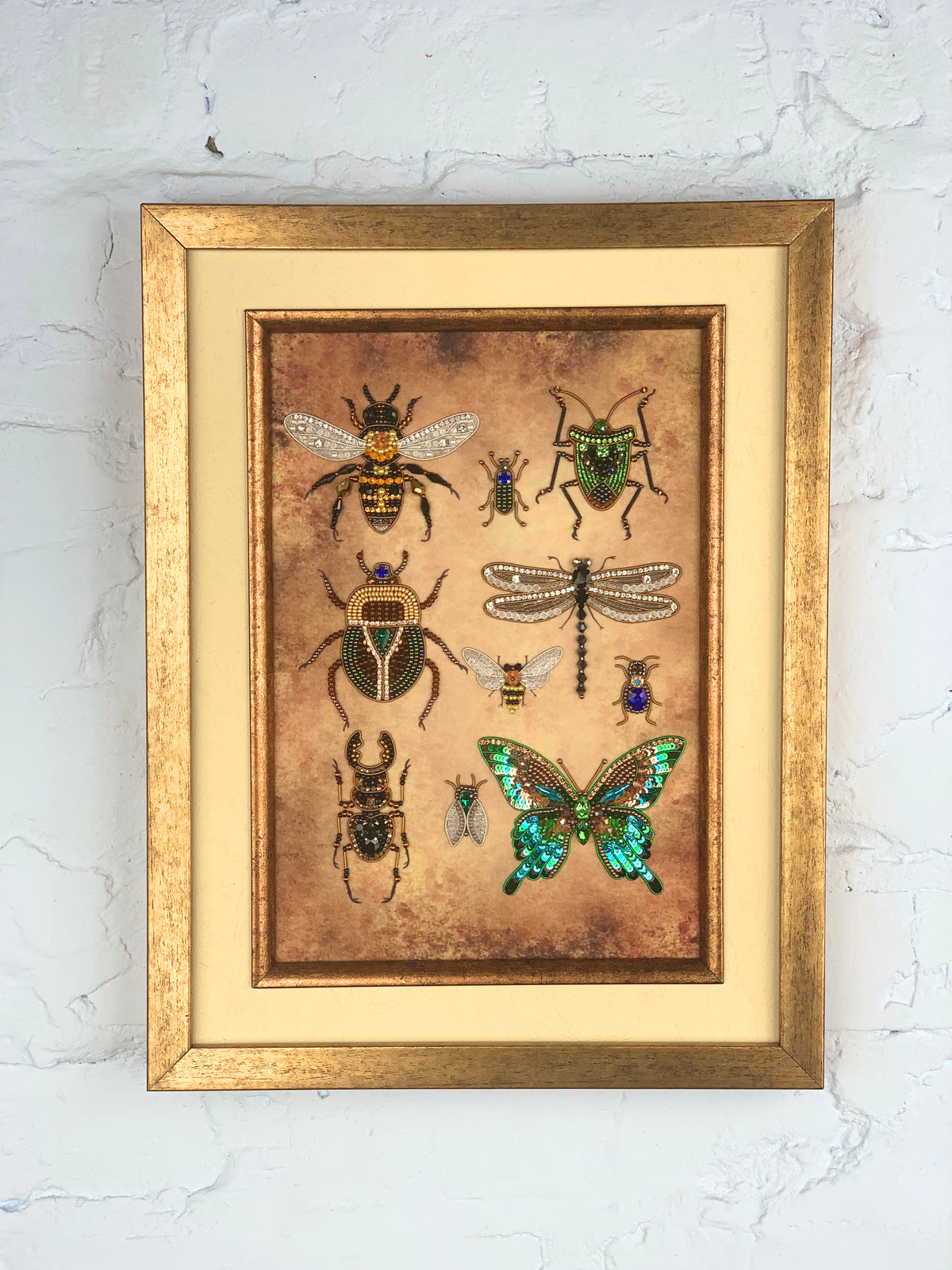 a framed collage of various insects, including bees, butterflies, and dragonflies, against a textured background.