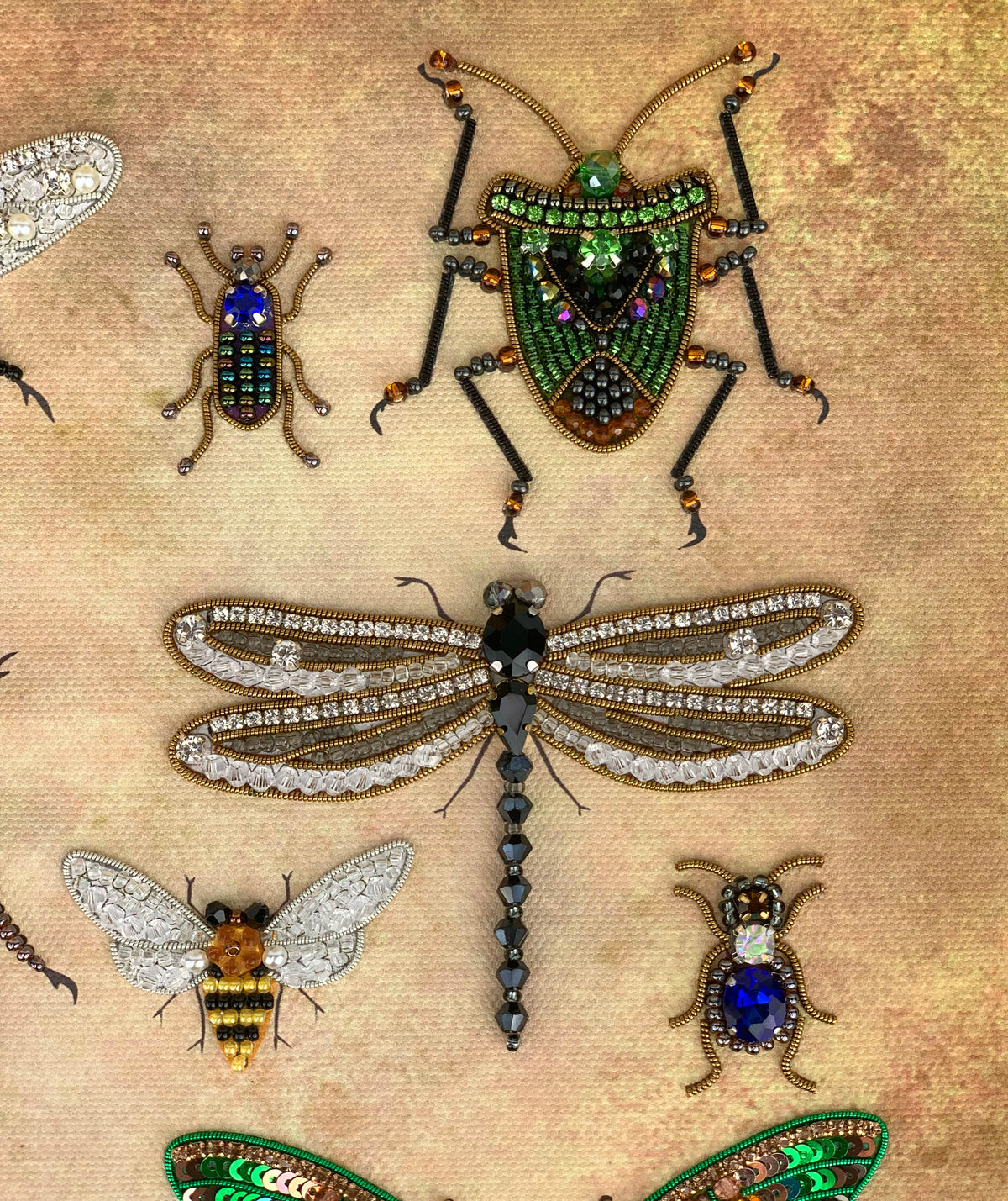 a collection of intricately designed insects, including a dragonfly, a bee, and several other insects, all adorned with sparkling jewels and beads.