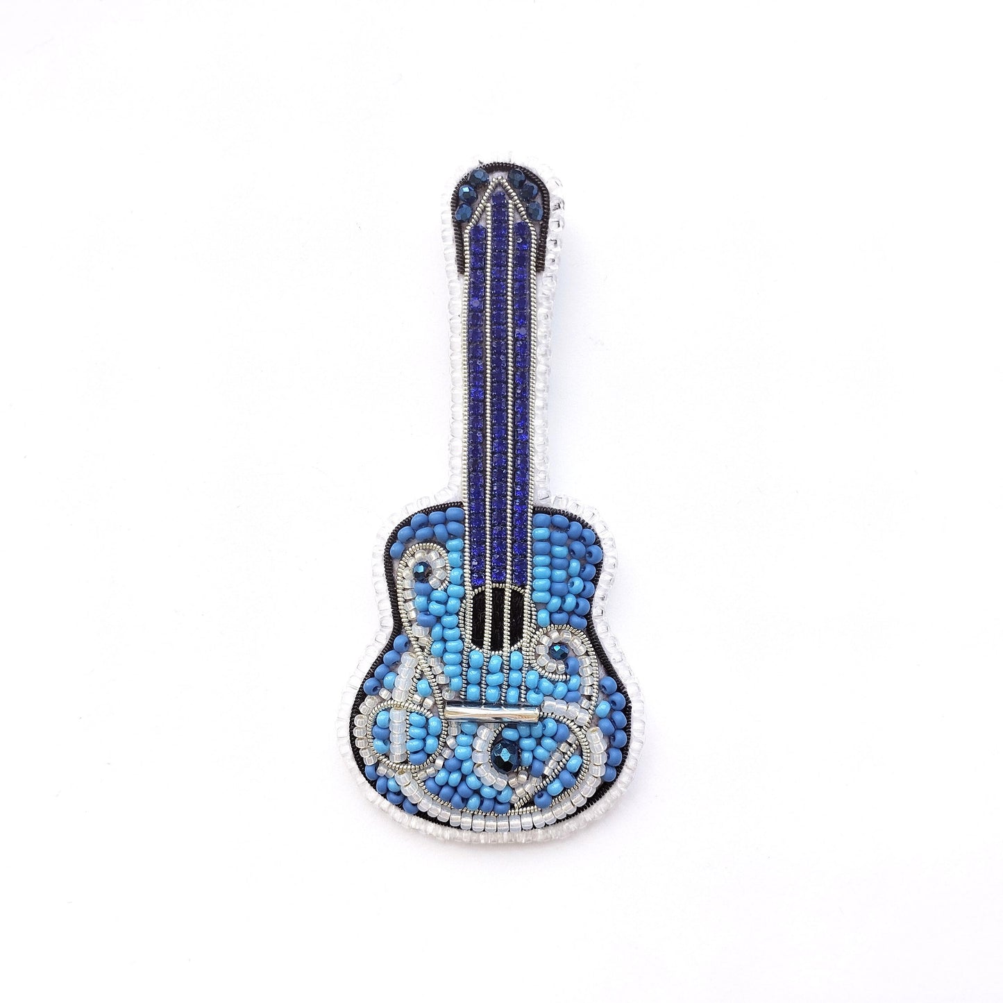 A blue and silver guitar-shaped brooch made of small blue beads and silver wire.