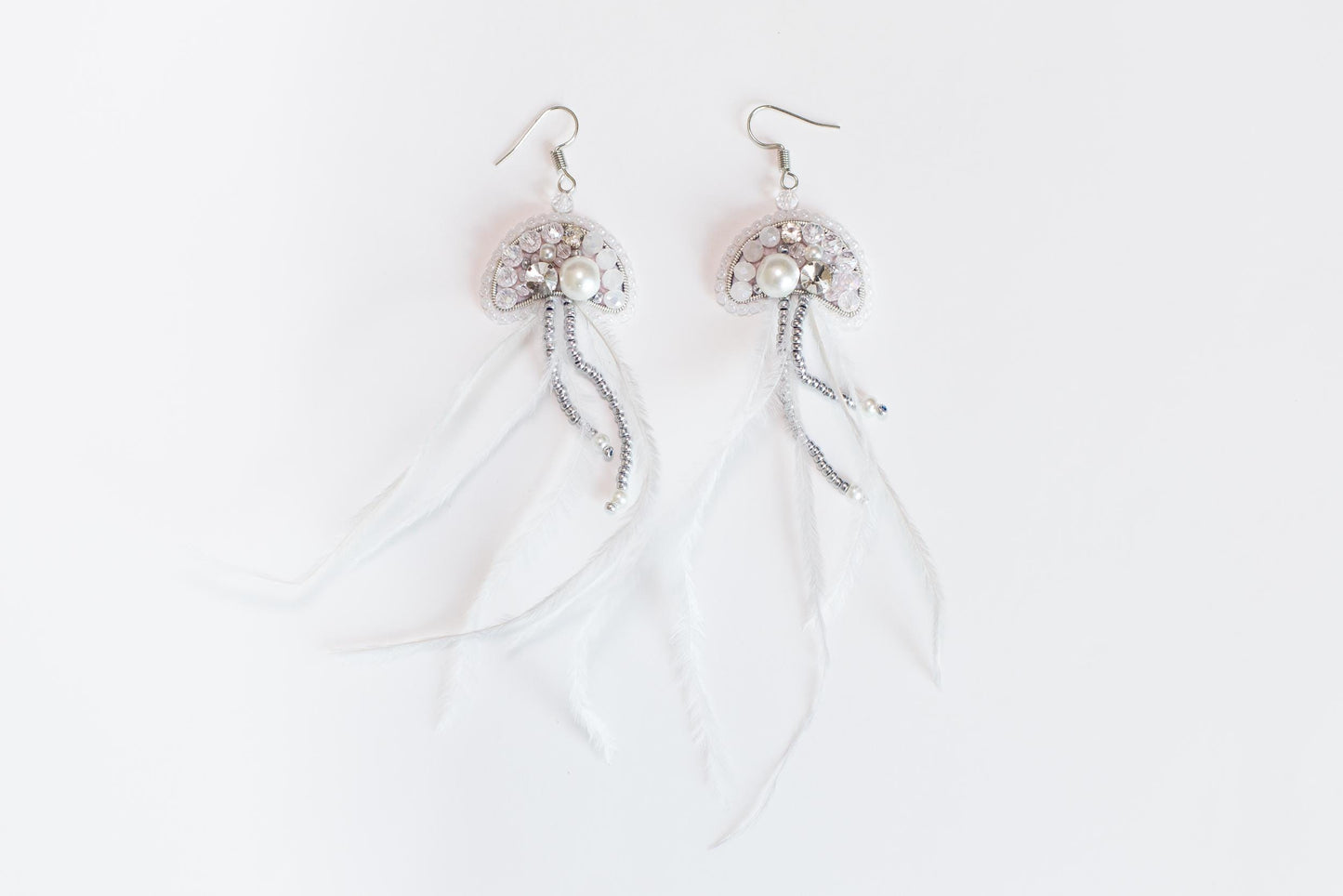 a pair of white feathers with beads and pearls