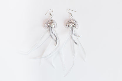 a pair of white feathers with beads and pearls