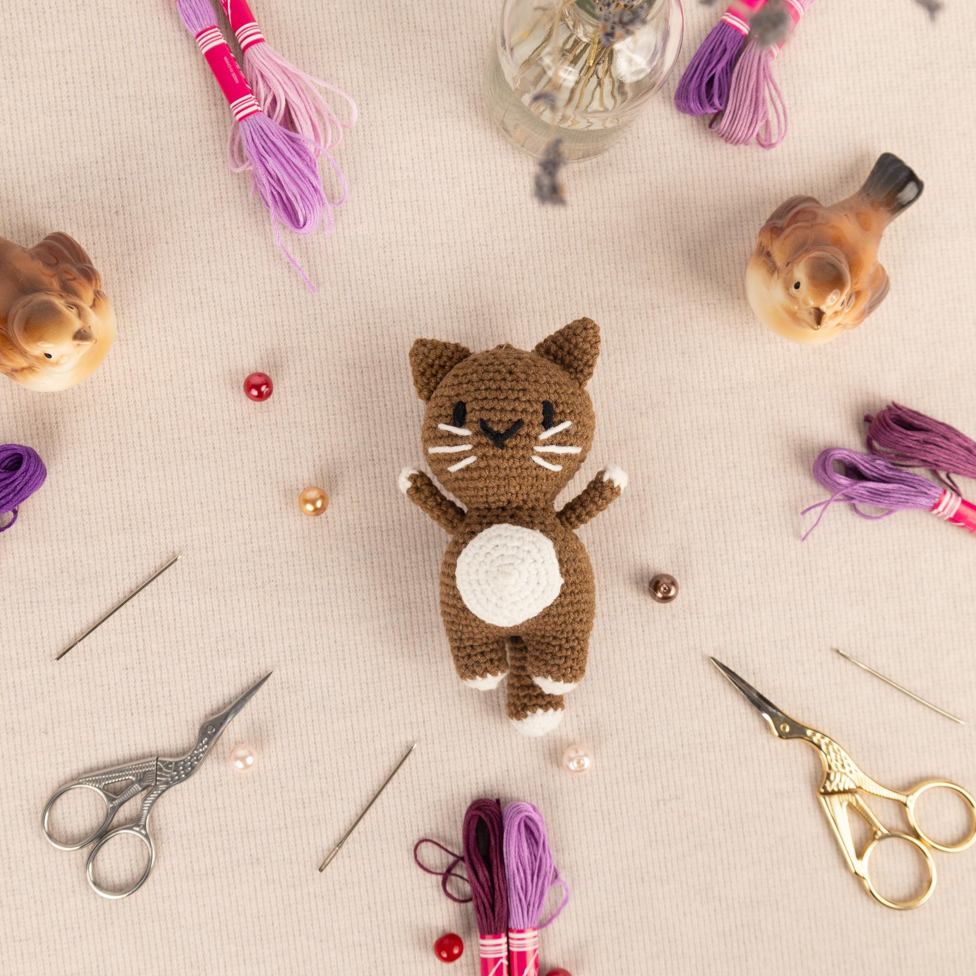 a crocheted cat sitting on top of a table next to a pair of