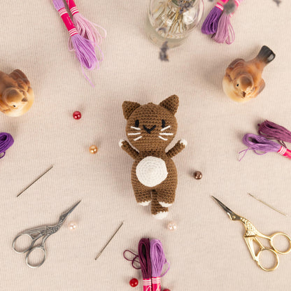 a crocheted cat sitting on top of a table next to a pair of
