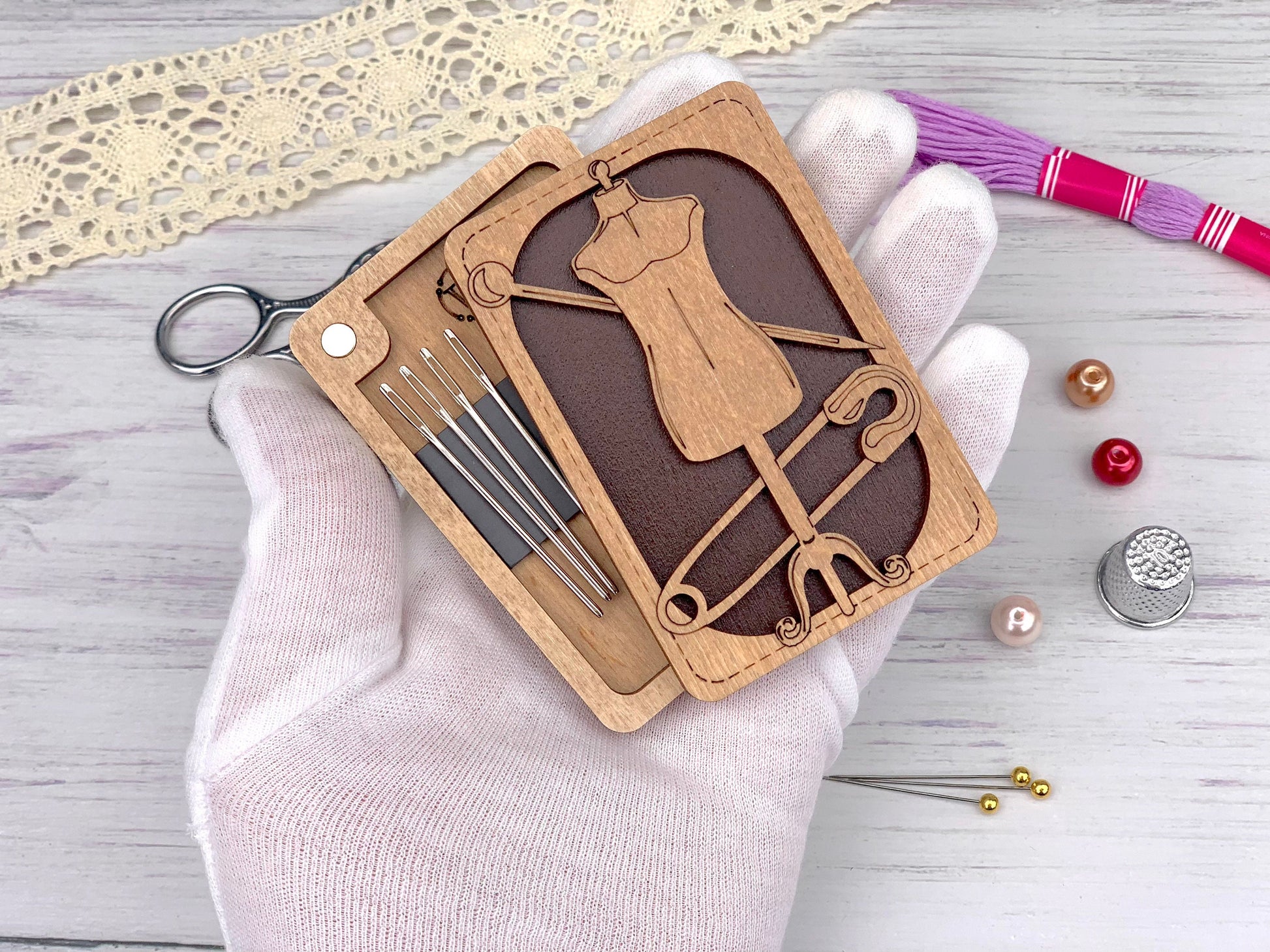 a hand holding a wooden cutout of a dressmaker